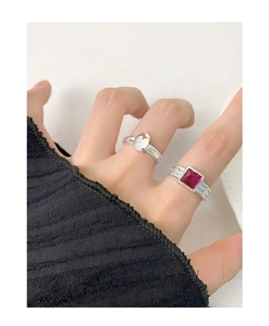 Close-up of stacked S925 silver rings featuring an oval opal and a square red zircon