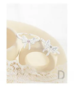 Macro shot of silver bow rings featuring pink and yellow zircon stones with lace background