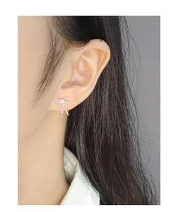 Close-up of S925 sterling silver bow earrings with zircon stones worn by a model