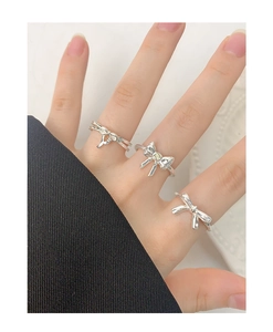 Detail of three-piece silver bow ring set with inset gemstone on a model hand