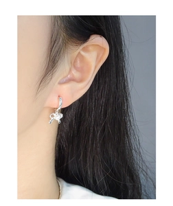 Close-up of elegant silver bow pearl earrings worn by a model in a side profile view