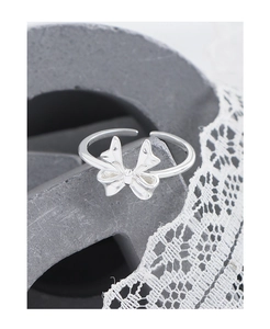 Macro detail of polished silver bow ring on stone texture with lace accents