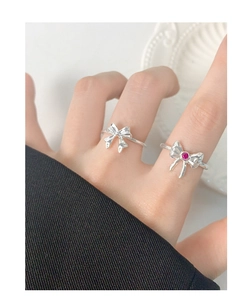 Detailed view of silver bow rings with red gemstone worn on hand in a stylish setting