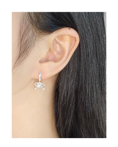 Close-up of S925 sterling silver bow earrings with pearl pendant worn by model