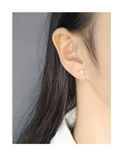 Close-up of a silver bow knot earring with zircon stone worn on a female model
