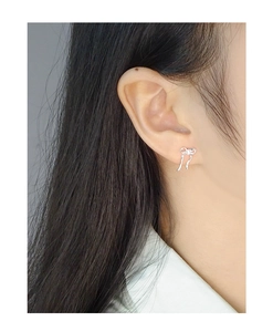 Close-up of elegant silver bow earrings with zircon and tassel on a female model