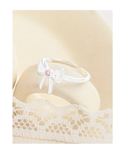 Macro detail of S925 sterling silver bow ring with pink gemstone and lace decoration