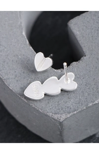 Macro shot showing S925 hallmark on asymmetric silver heart earrings on stone base