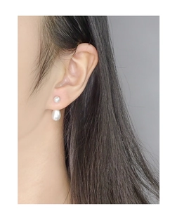 Primo piano di eleganti orecchini a doppia perla in argento S925 su modella