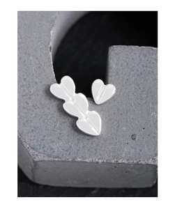 Macro shot of asymmetric S925 silver heart earrings on dark textured stone