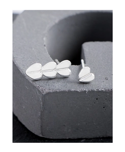 Macro shot of asymmetric silver heart earrings on dark grey stone background