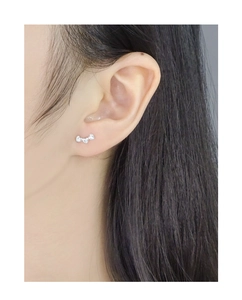 Close-up of minimalist silver triple heart stud earrings worn on a model's earlobe