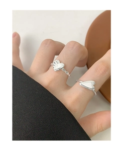 Detail of silver heart rings with pleated texture and polished finish on hand