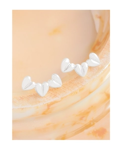 Macro detail of three silver heart studs with textured finish on marble background