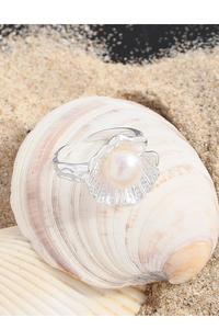 Macro detail of S925 silver shell ring with pearl accent on beach sand background