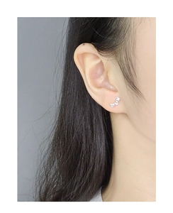 Close-up of triple heart sterling silver stud earrings worn on a model's ear