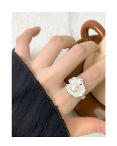 Detail of S925 silver shell ring with round pearl shown on finger with coffee cup