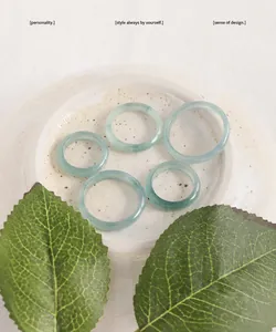 Macro view of five translucent green natural jade rings on a minimalist ceramic tray