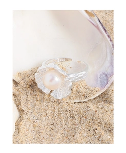 Close-up of S925 sterling silver shell ring with pearl and textured band on sand