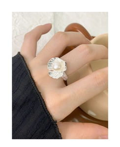 Close-up of S925 silver shell ring with pearl detail on hand holding a coffee cup