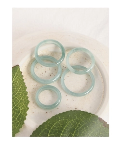 Detailed view of minimalist light green natural jade rings in a ceramic dish