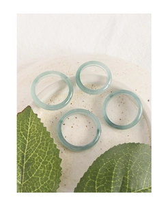 Close-up of four translucent light green jade rings on a decorative ceramic plate
