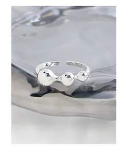 Close-up of S925 sterling silver open ring with three spheres on a water ripple glass tray