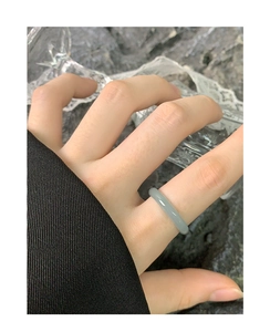 Detail view of a minimalist blue-grey natural jade band ring worn by a model