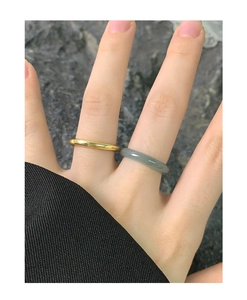 Minimalist gold metal and grey-green jade ring set shown on hand in natural light