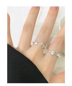 Detailed view of silver heart and shell adjustable open rings worn on model fingers