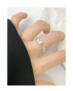 Detail of silver S925 flower heart open ring worn on finger against black and lace background