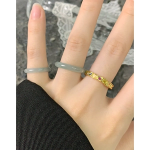 Minimalist natural jade and gold rings set with colorful gemstones on a woman's hand