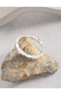 Detailed macro of S925 silver flower ring showcasing polished textures on natural stone