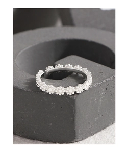 Macro shot of silver daisy chain ring with textured floral details and open band design