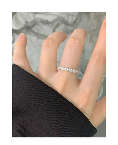 Detail of S925 sterling silver floral ring with small daisy patterns worn on a finger