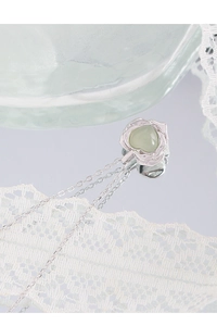 Détail du collier en argent S925 avec pétales de rose autour d'un pendentif cœur vert