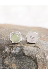 Macro shot of S925 sterling silver stud earrings with green gemstone on natural rock