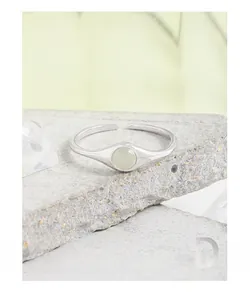 Detail of S925 sterling silver ring with light green crystal on a stone surface