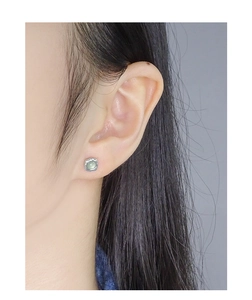 Detail shot of a S925 silver stud earring with a pale green crystal and ruffled texture