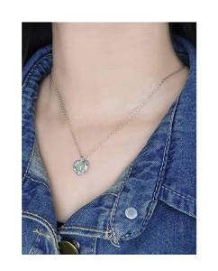 Gros plan du collier coeur en argent S925 avec pierre précieuse vert clair au cou