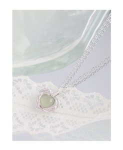 Détail macro du collier cœur en argent S925 avec cristal vert clair sur dentelle