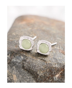 Macro detail of S925 silver earrings with green gemstone and hammered texture