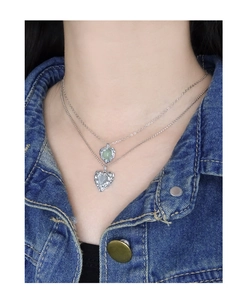 Détail de colliers superposés en argent S925 avec pendentifs cœur et cristaux verts
