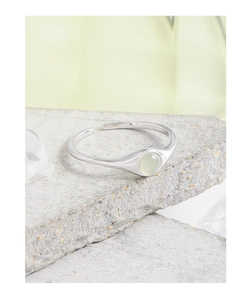 Close-up of minimalist S925 silver ring with a light green crystal on a natural stone