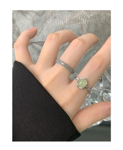 Dettaglio di un anello in argento S925 con gemma verde e una fascia grigia trasparente
