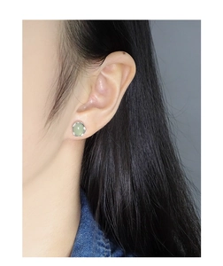 Close-up of S925 silver stud earrings with round green crystal stone on female model