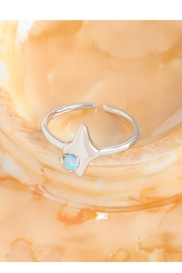 Macro de la bague étoile en argent S925 avec opale bleue sur verre ambré texturé