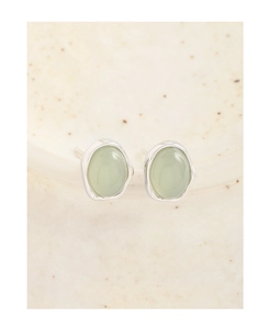 Macro detail of S925 silver stud earrings featuring light green crystal in irregular setting