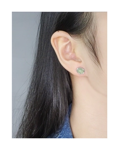 Close-up of minimalist S925 silver stud earring with oval light green crystal on ear