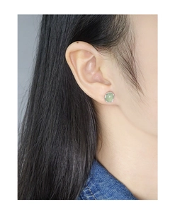 Close-up of minimalist light green crystal stud earring on model with silver organic frame